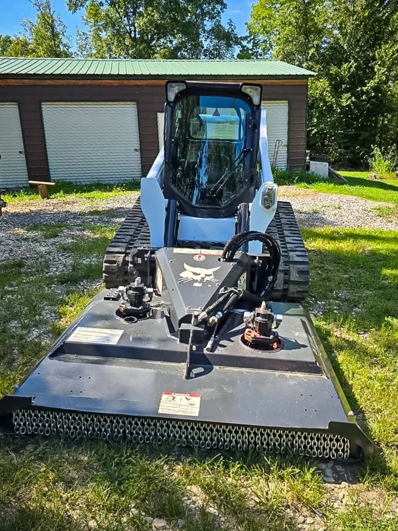 Front view of a Bobcat T740 track loader with a brush cutter attachment