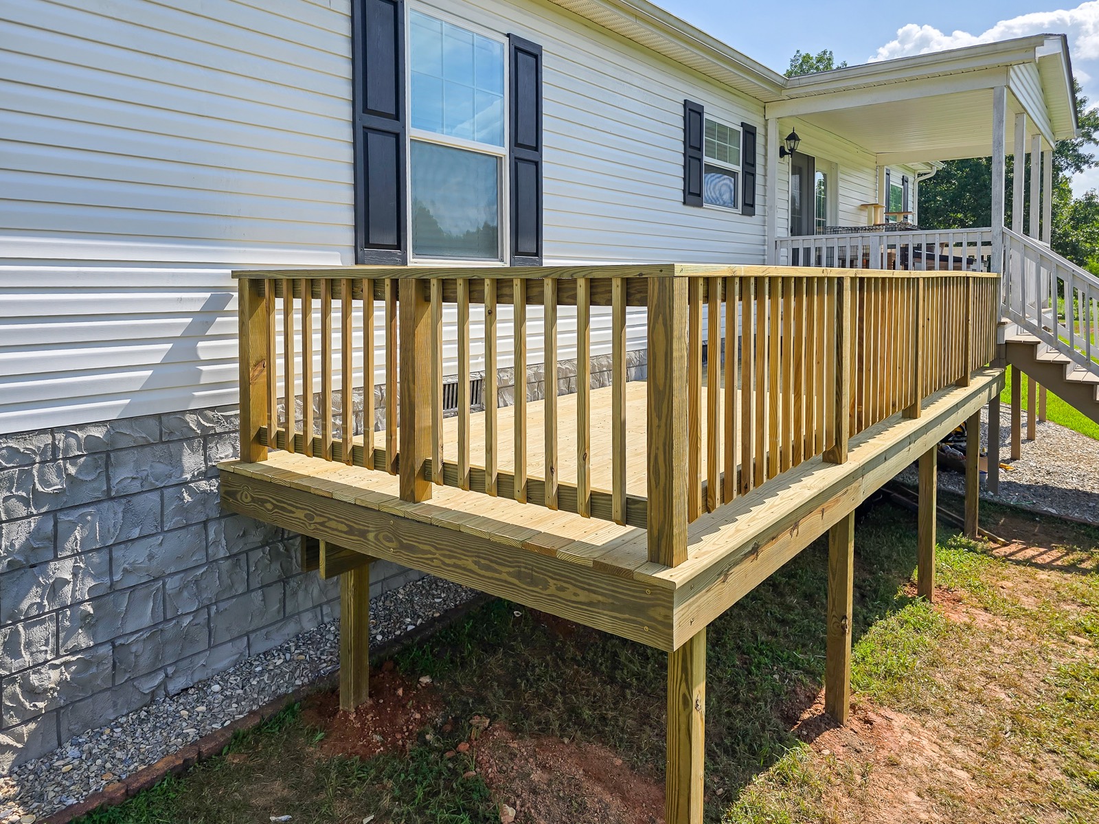 New elevated deck with full perimeter railings beside an existing porch
