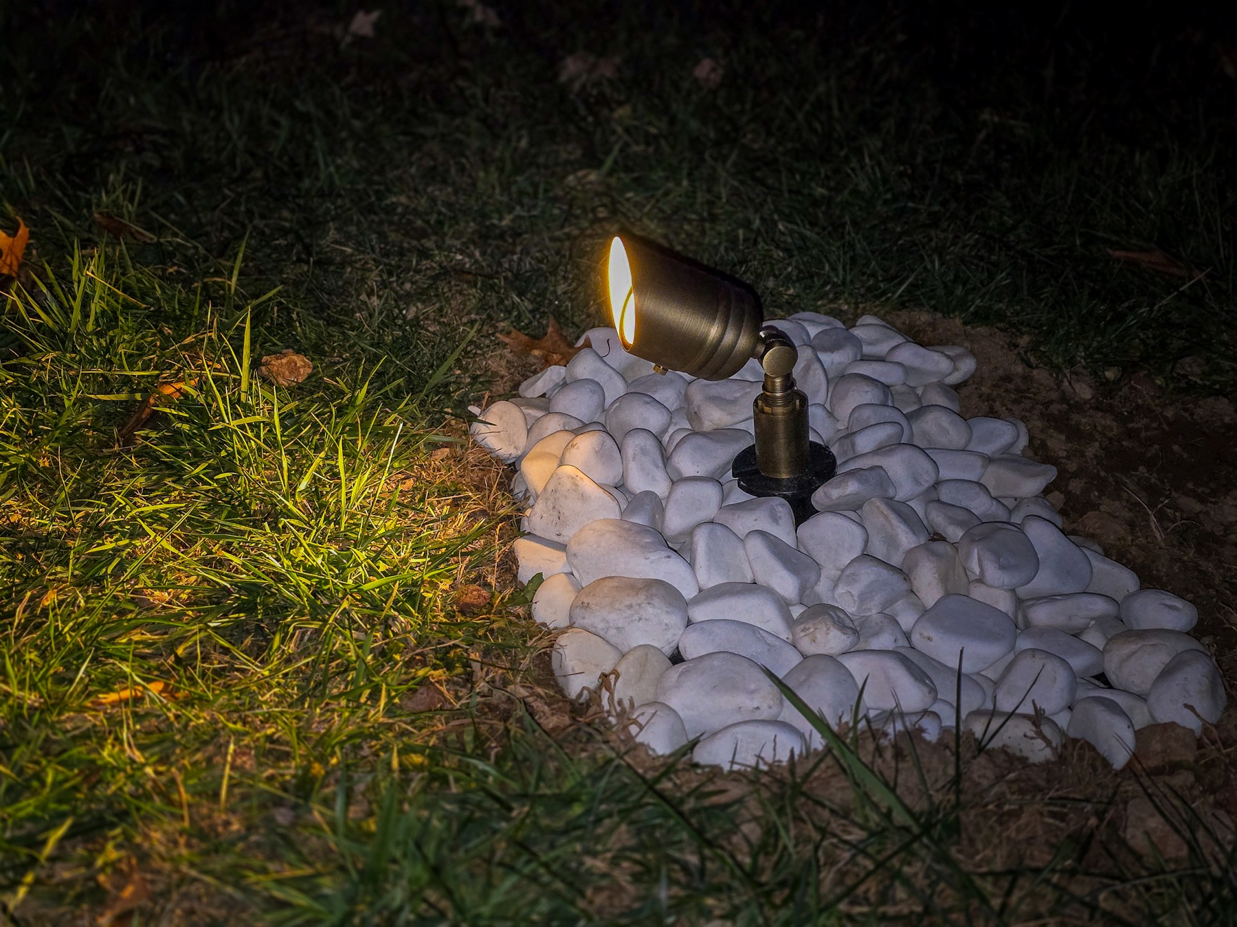 Ground-mounted landscape spotlight aimed across grass at night