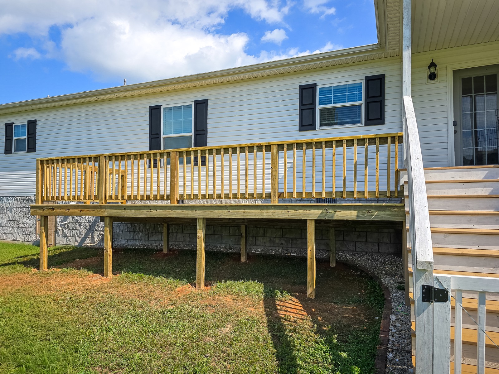 Long elevated wood deck with posts and railings beside a home
