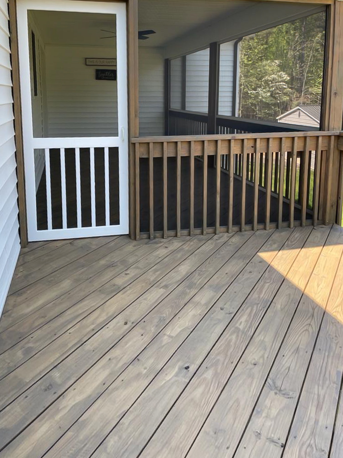 Covered porch with lightly finished deck boards and a screened enclosure